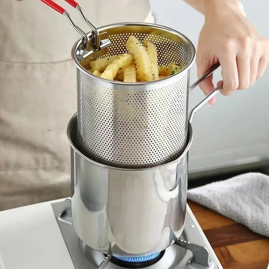 Stainless steel deep fryer basket with French fries on a gas stove.