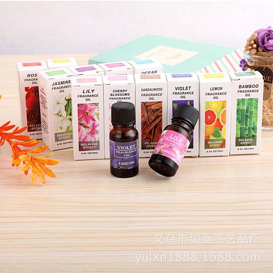 Assorted fragrance oil bottles and boxes on a wooden surface with a light background.