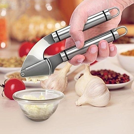 Hand using a garlic press with garlic and ingredients on a kitchen counter