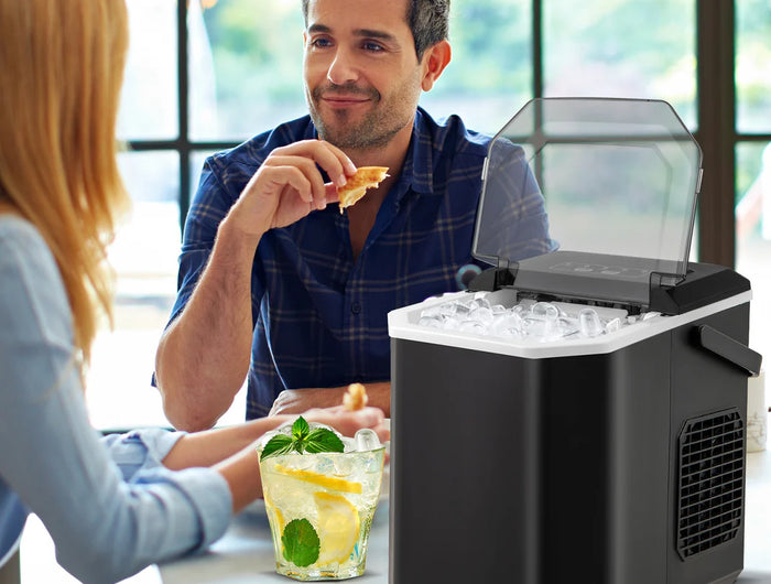 Man and woman sitting at a table with a portable ice maker in front of them.