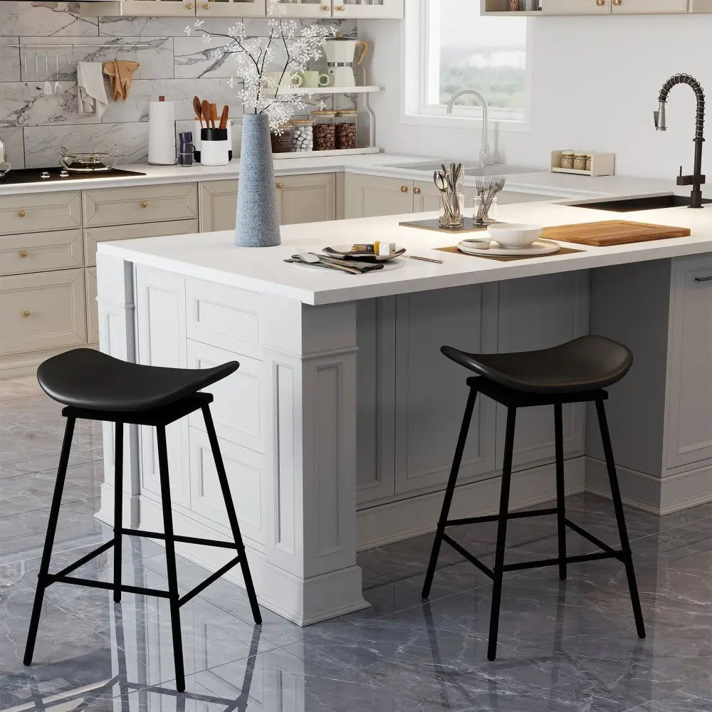 Modern kitchen with a white island, black bar stools, and various kitchen items.